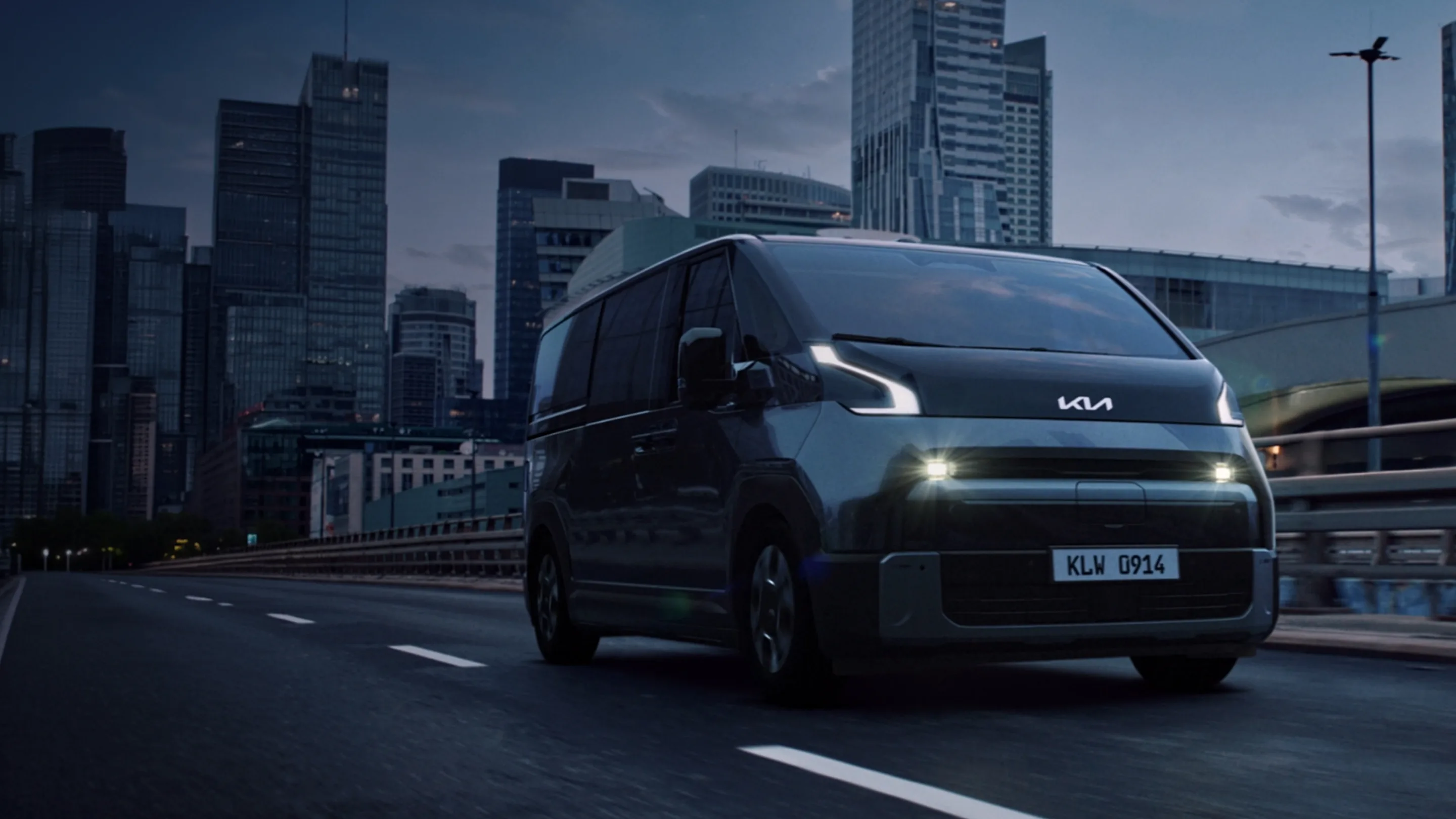 Kia PV7 rijdend door de stad bij avond